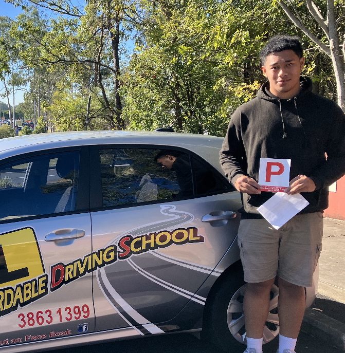 New driver holding a red P plate and his test paperwork beside an Affordable Driving School car