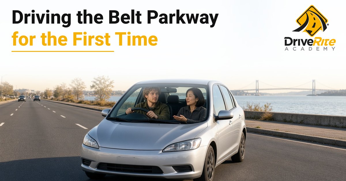 A driving instructor in a gray fleece talks calmly with a young man driving a silver sedan on a waterfront parkway in Brooklyn, with a large suspension bridge in the distance.