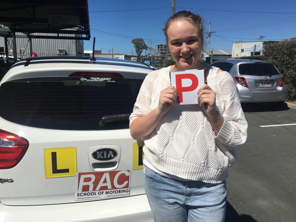 RAC student holding a red P plate beside a learner car
