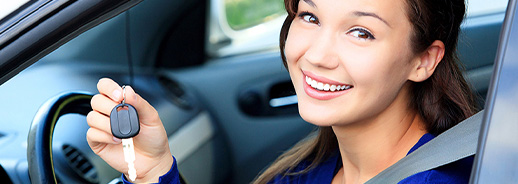 A licensed young woman smiling while holding the car key.