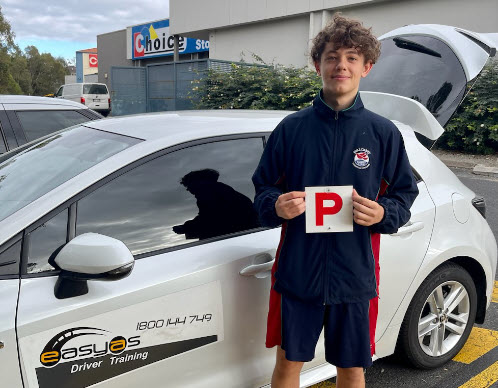 Young man holding a red P plate beside an EASYAS car