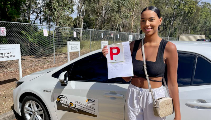 Woman holding a red P plate beside a white EASYAS car