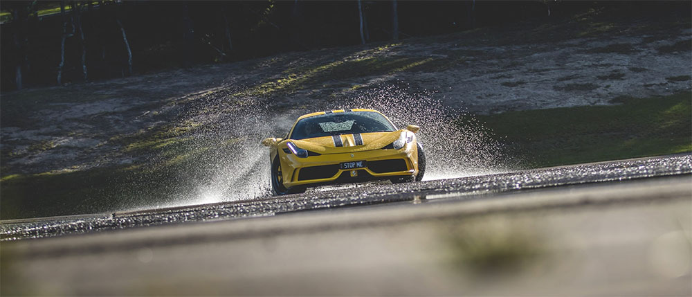 Yellow sports car spraying water on a skid pan.