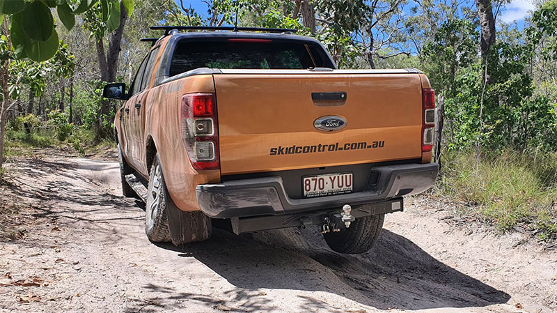 An orange 4WD truck driving over a muddy track.