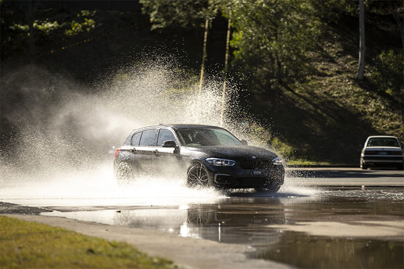 Black car skidding through water on a skid pan.