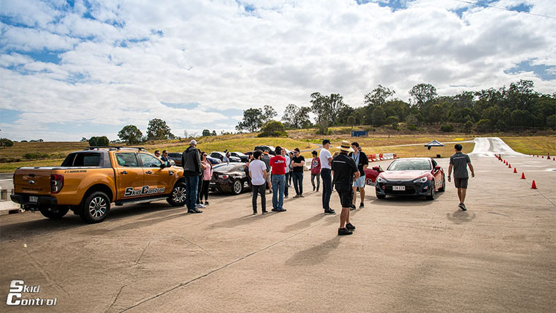 Skid Control participants gather around cars.