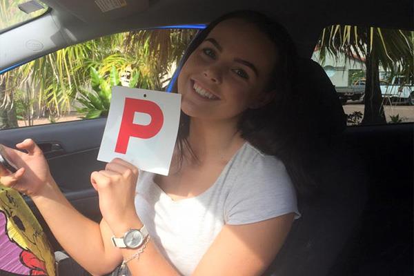 Student holding a red P plate inside a training car