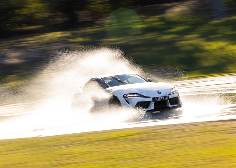 White car skidding through water on a skid pan.