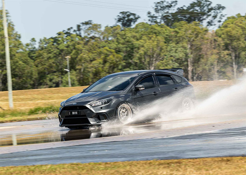Black car skidding through water on a skid pan.