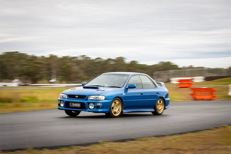 Blue car accelerating on a race track.