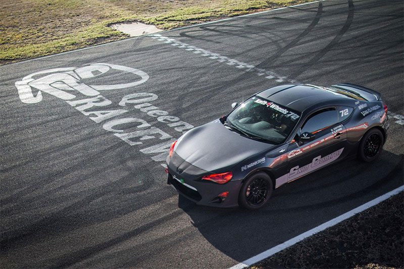 Aerial view of a black sports car parked on Queensland Raceway race track.