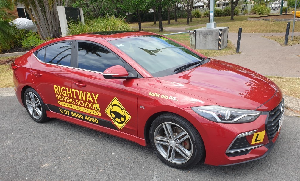 Red Rightway-branded car photographed from the front and side in an outdoor parking area.