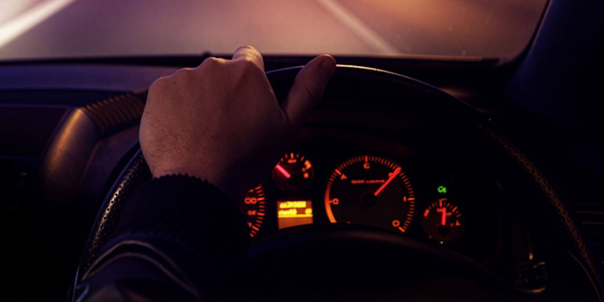 Night driving lesson in Parramatta with a man's hand on the steering wheel.