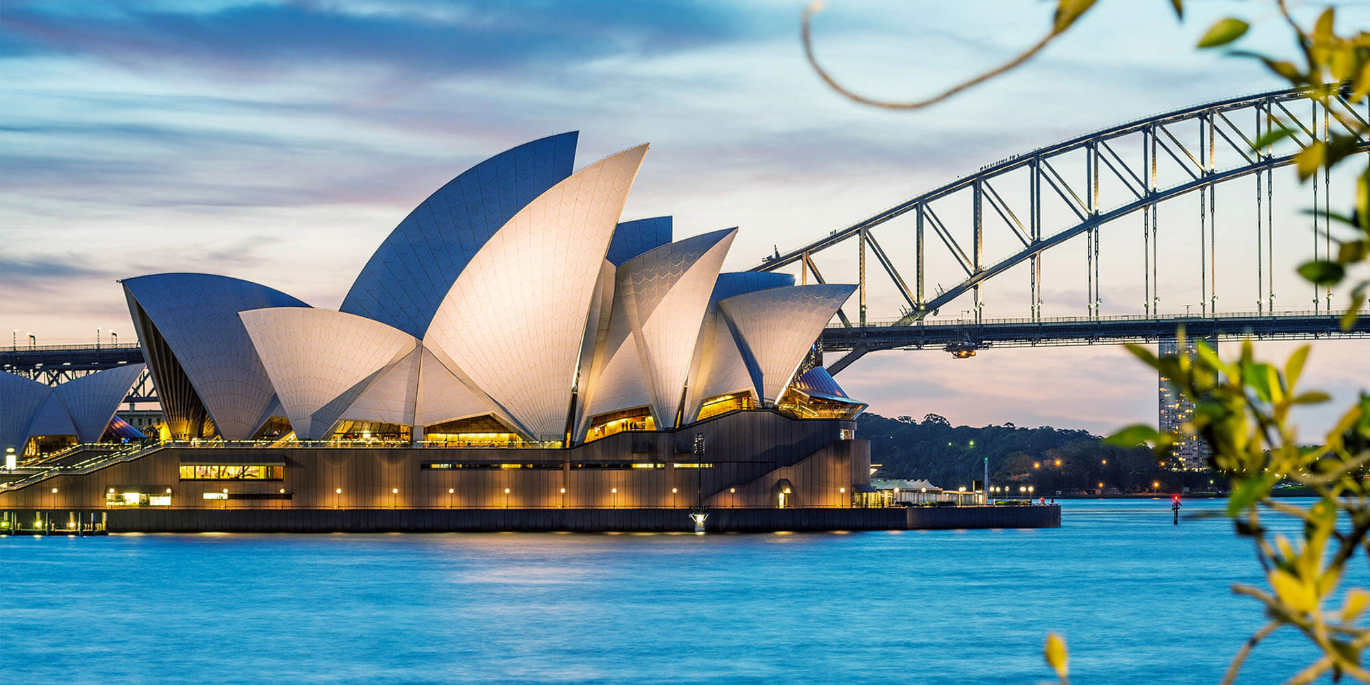 Sydney Opera House seen from across the blue waters of Sydney Harbour.