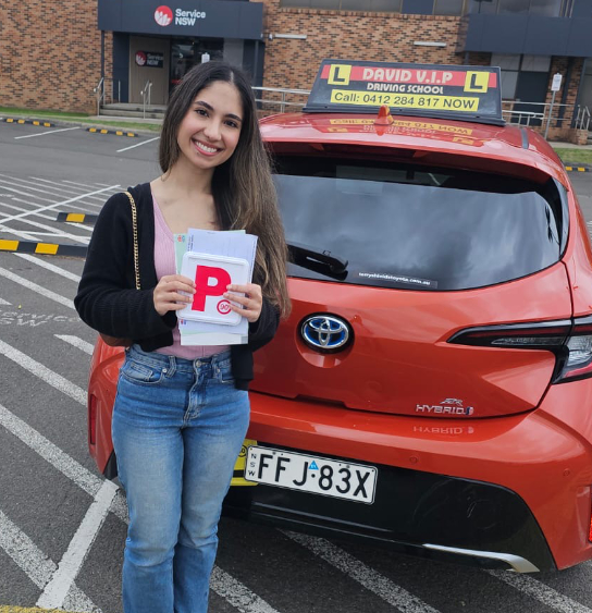 Happy student stands in front of a red Driving Lesson car after passing her Driving Test in Parramatta.