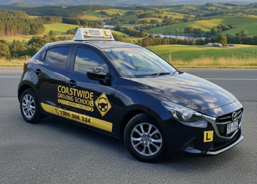 Dark blue Coastwide learner hatchback with countryside behind