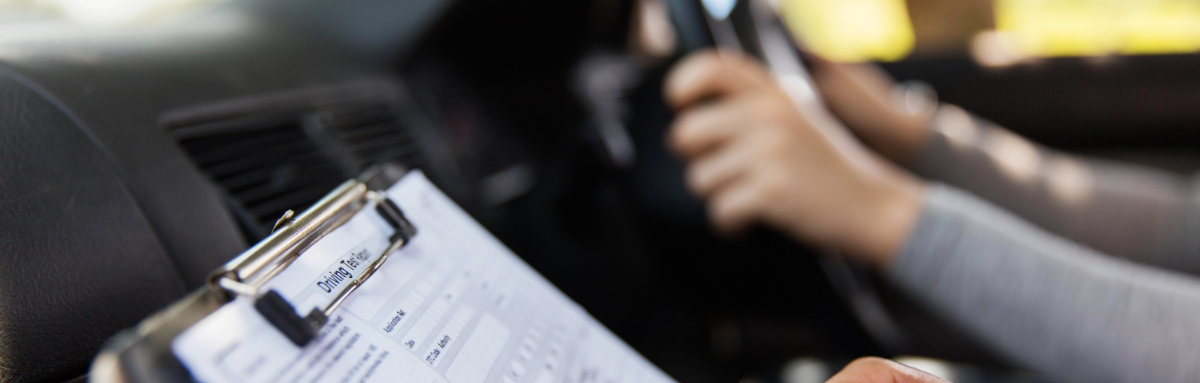 Inside a car on a driving test day, focus on the test sheet and hands on the steering wheel.