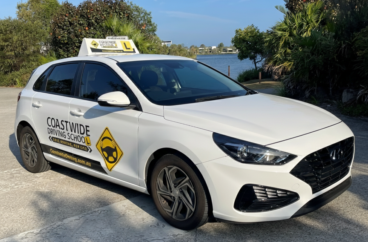 White Coastwide learner hatchback with water and trees behind it