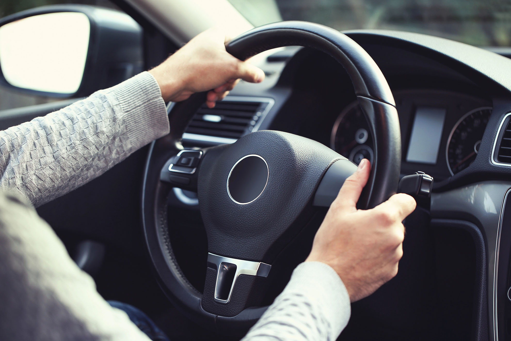 Close-up of a driver's hands on a steering wheel during a behind-the-wheel training session.