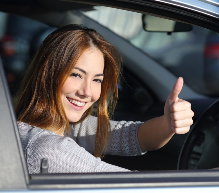 Lady on a driving lesson shows a thumbs up and smiles.
