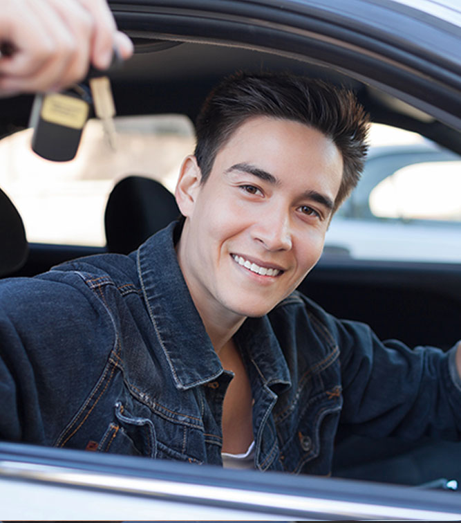 Lady on a driving lesson shows a thumbs up and smiles.