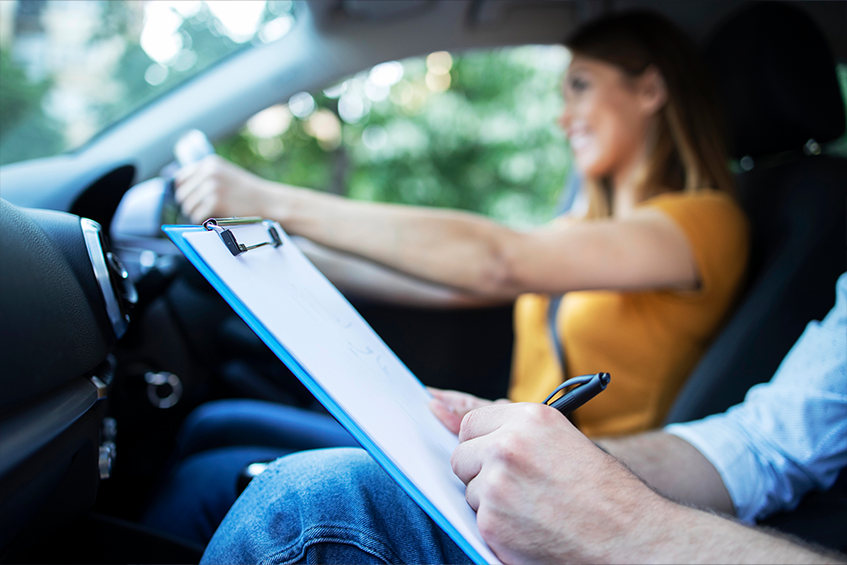 Student taking their driving test with check sheet in foreground.