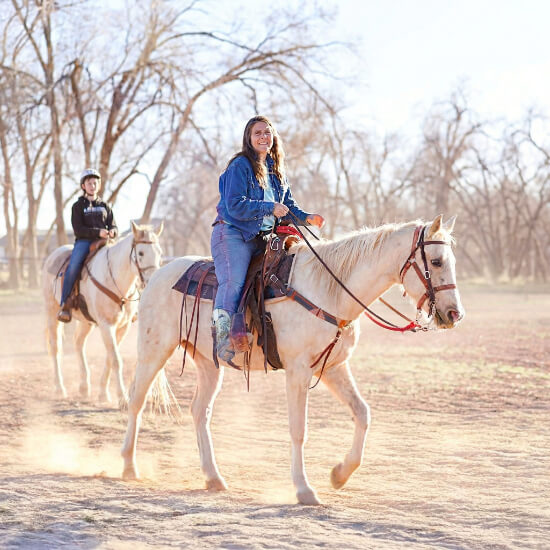 Two riders on horseback at K&J Horse Boarding in Cedar City, Utah.