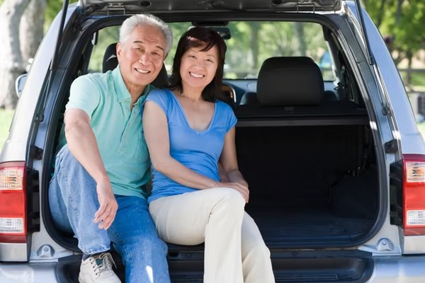 Senior couple smiling while seated in the back of an open SUV.