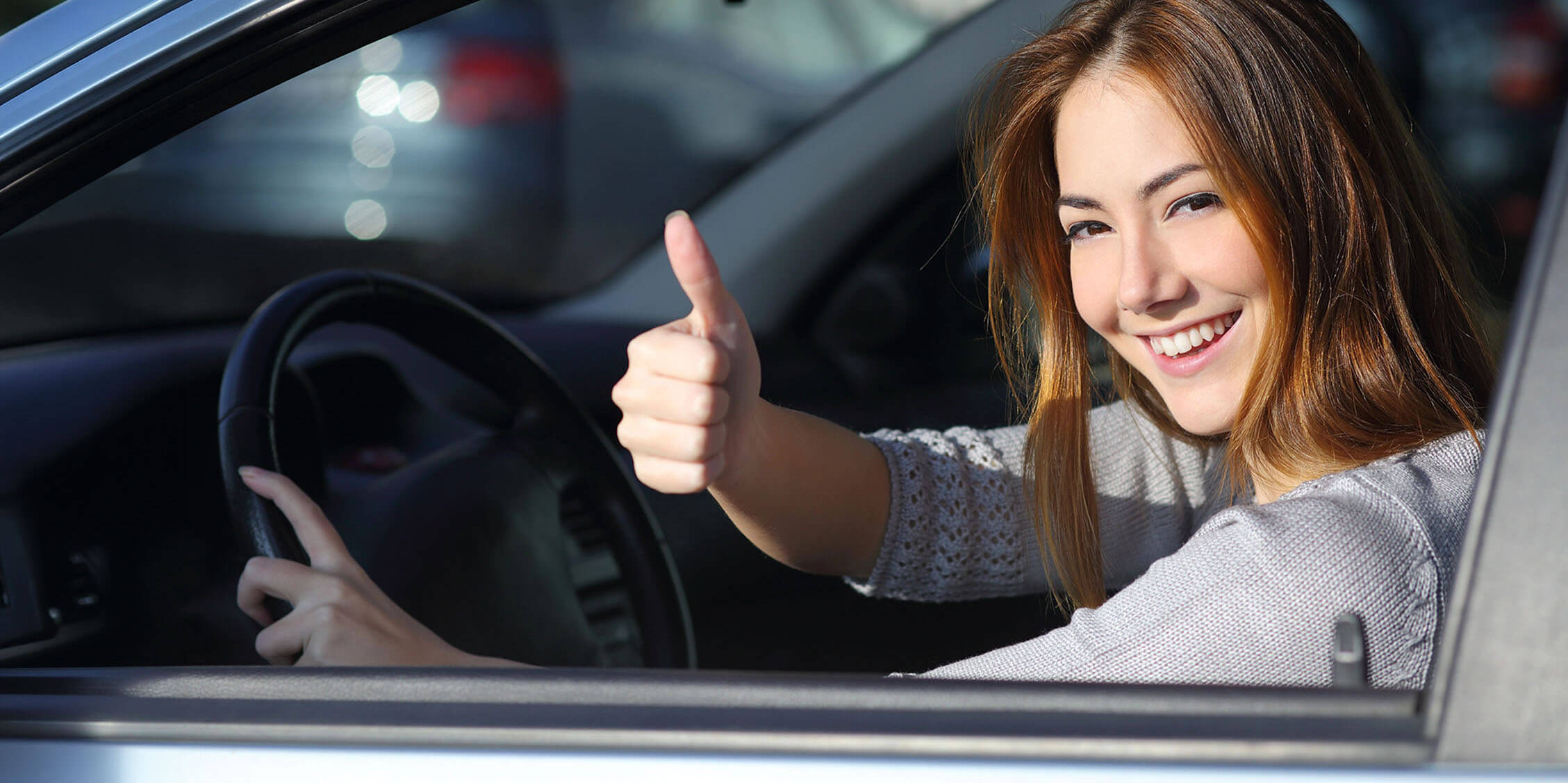 Teen driver smiling from a car window