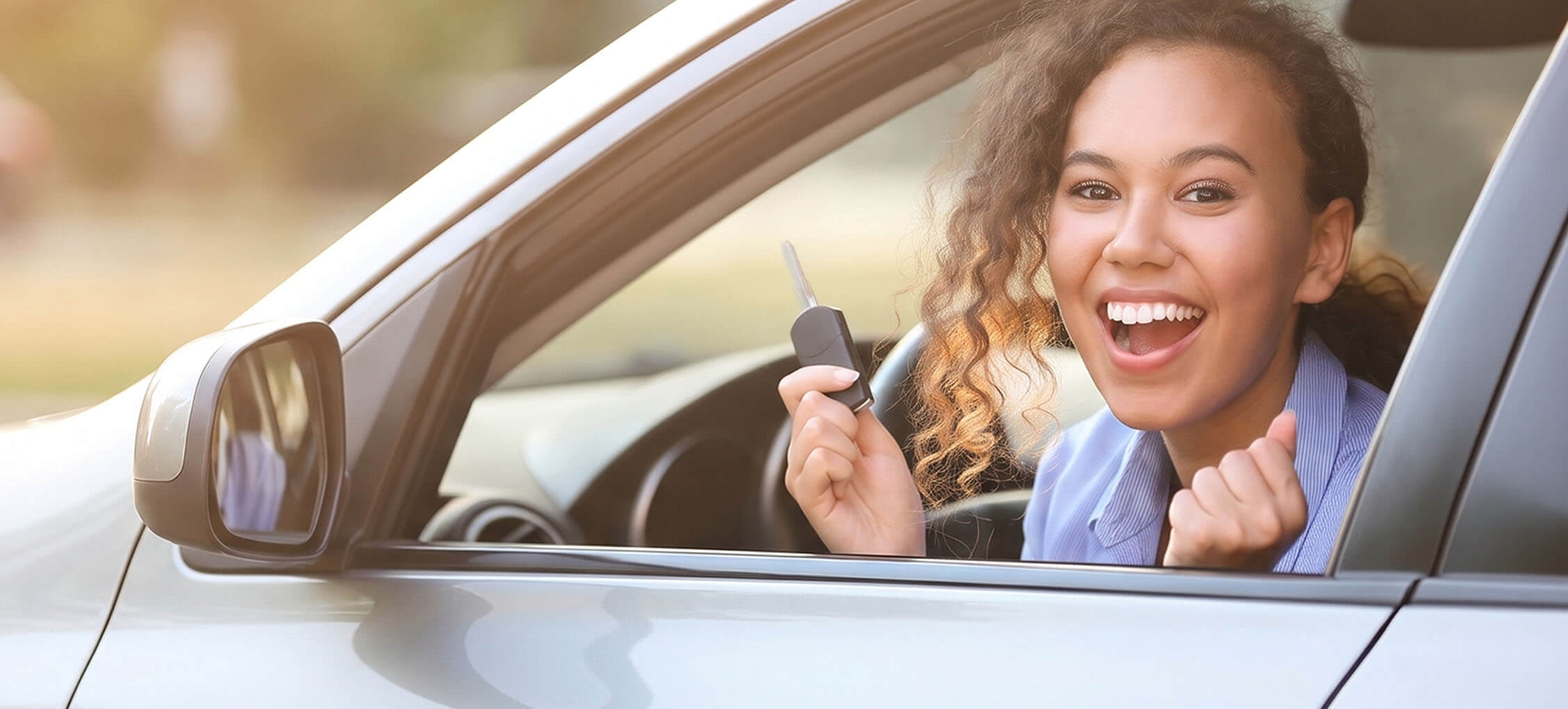 Teen driver smiling from a car window