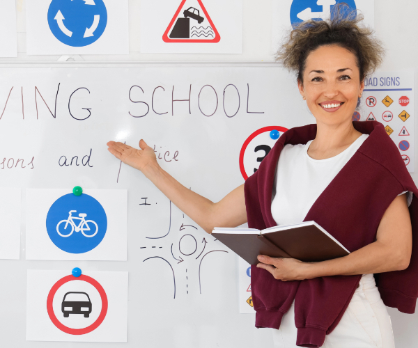AAA driving instructor teaching road signs on a classroom whiteboard during a lesson.