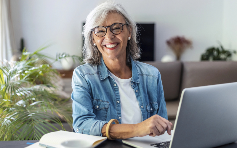 Senior student smiling while doing the Online Driver Improvement Program Course on a laptop at home.