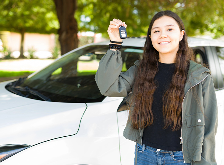 Adult instructor pointing ahead while a teen student practices driving.