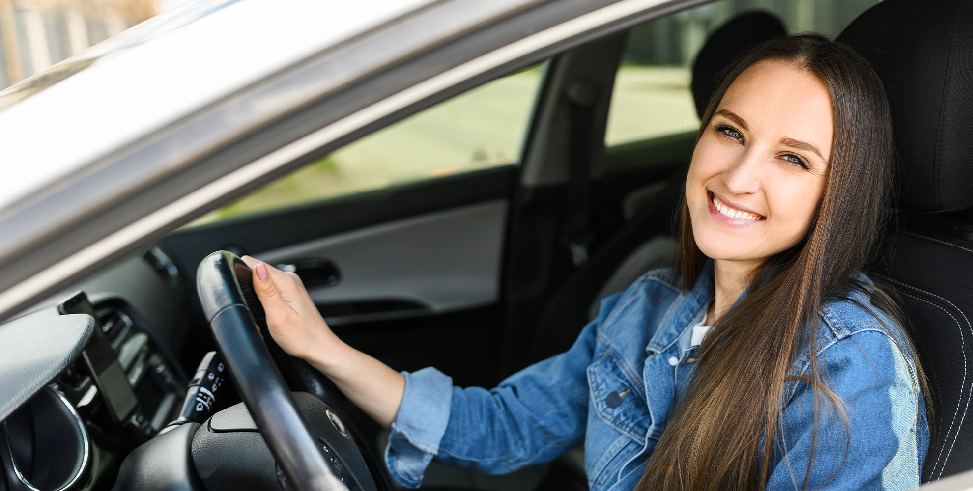 Teen driver smiling from a car window