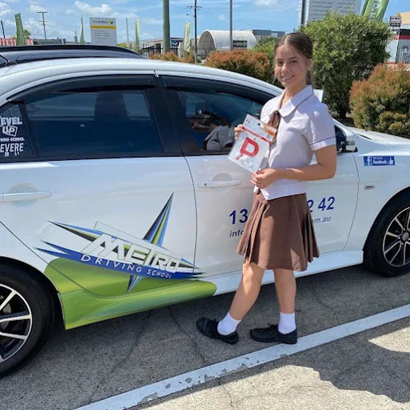 A Metro Driving School learner with their P-plates beside the car