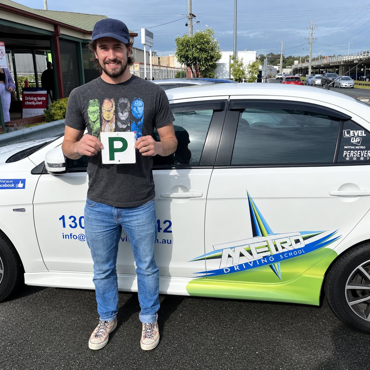 A Metro learner holding a green P-plate beside a Metro dual-control car at a Brisbane test centre after passing the driving test
