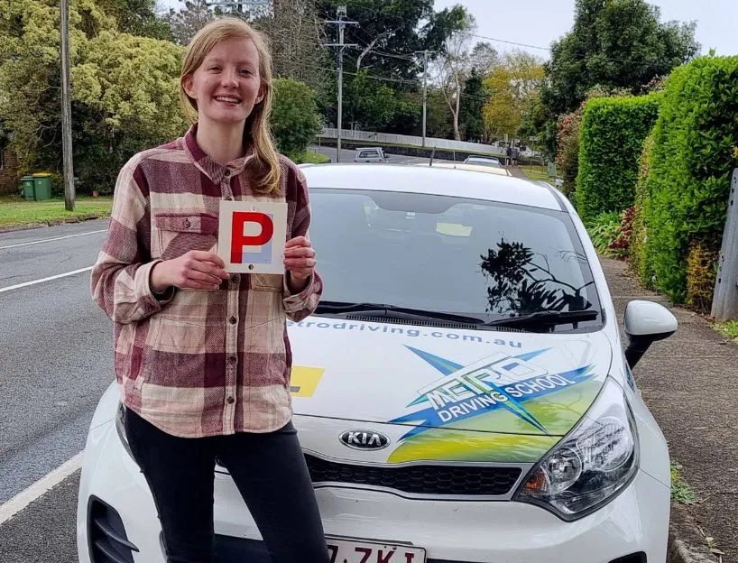 A Metro Driving School learner with a green P-plate beside a dual-control car in Thorneside after passing the driving test