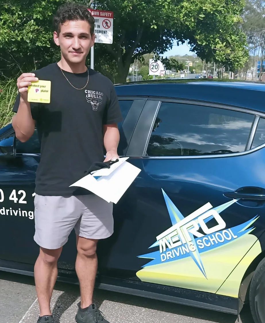 A Metro Driving School learner with a green P-plate beside a dual-control car in Wellington Point after passing the driving test