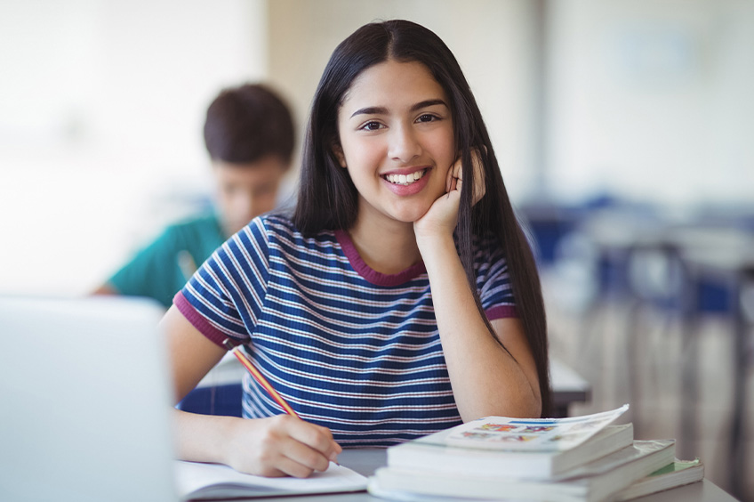Smiling student taking notes during a 30-hour classroom driving course