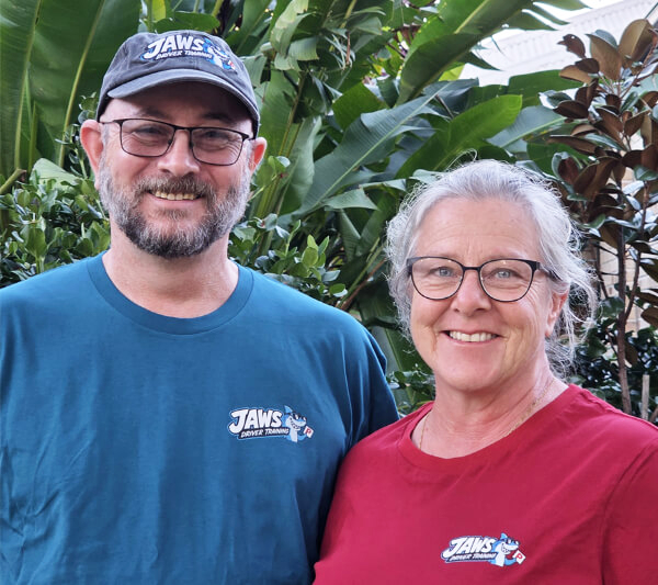 Driving Instructors Jacqui and Warren, smiling in their Jaws Driver training shirts.