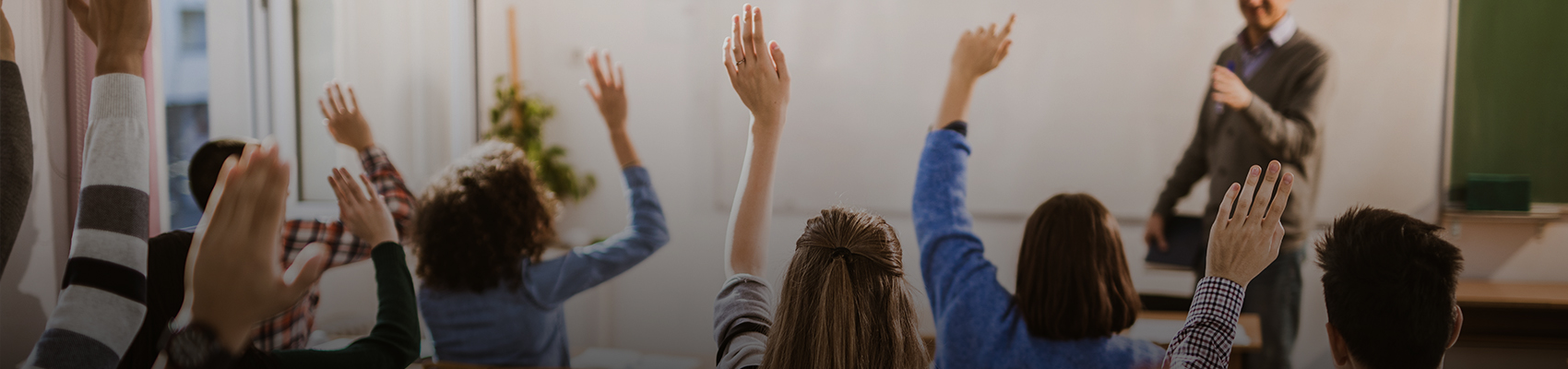 Instructor leading a classroom discussion as students raise their hands during a AAA 5-Hour Pre-Licensing course.