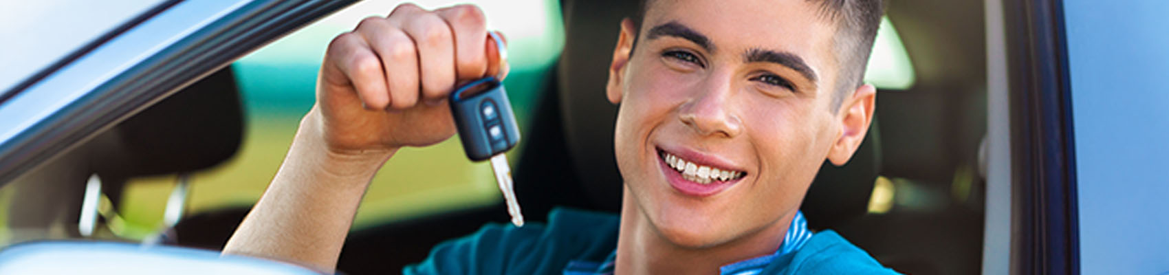Smiling teen driver holding car keys, ready to start his AAA Licensed to Learn online course.