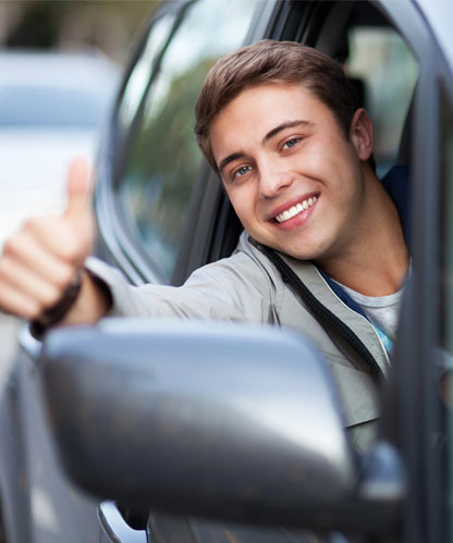 Learner driver smiling and giving a thumbs up from the driver's seat of an automatic lesson car