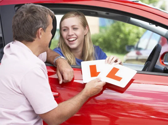 Learner and instructor holding up L plates beside a dual-controlled test car