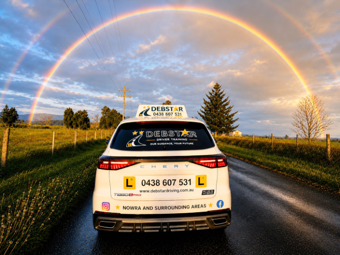Debstar Driver Training car on an open road with a double rainbow in the sky.