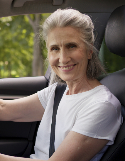 An older driver smiling from the driver's seat of an automatic lesson car