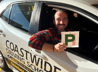 Driver holding a green P plate from a Coastwide car